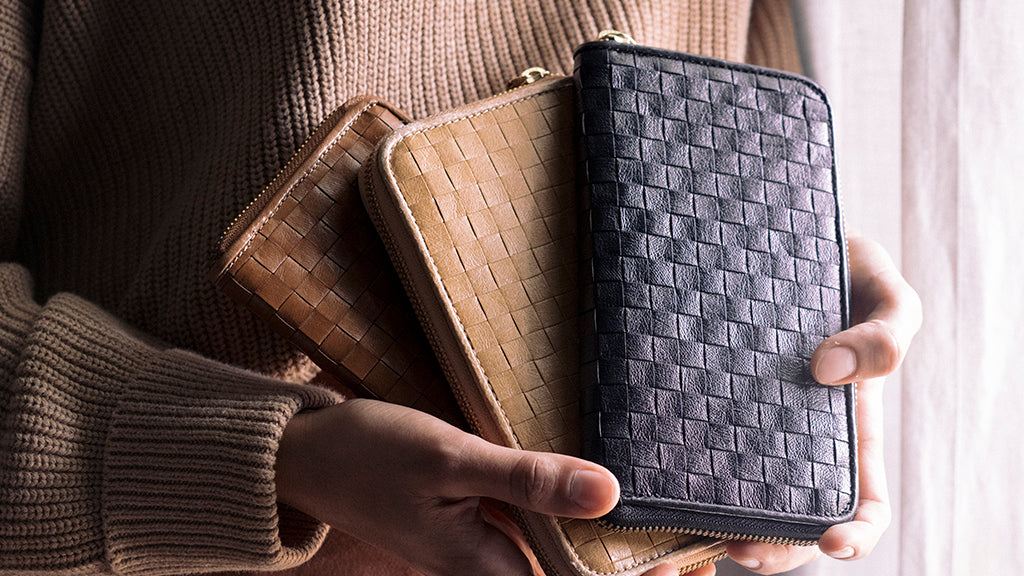 Three woven washable paper wallets are held by a woman in a camel jumper.