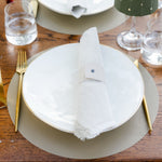 Dining table setting with white plates, gold cutlery, and a green lampshade.