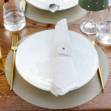 Dining table setting with white plates, gold cutlery, and a green lampshade.