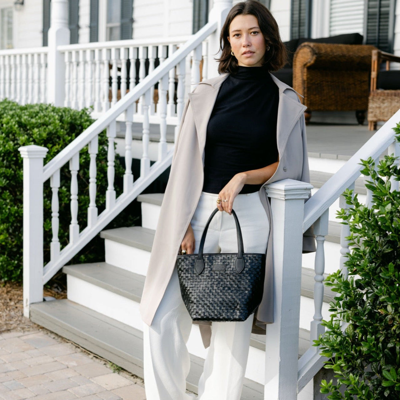 Woman holding a black handbag on a white staircase