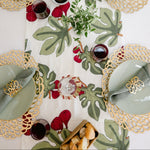 Decorative table setting with green leaf pattern, gold rimmed plates, and red accents.