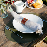 Table setting with a plate, fork, napkin, and coffee on a wooden table outdoors.