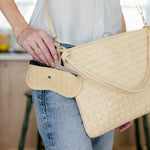Person holding a beige woven handbag in an indoor setting