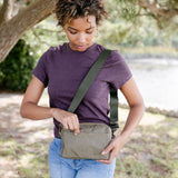 Woman holding a green crossbody bag outdoors