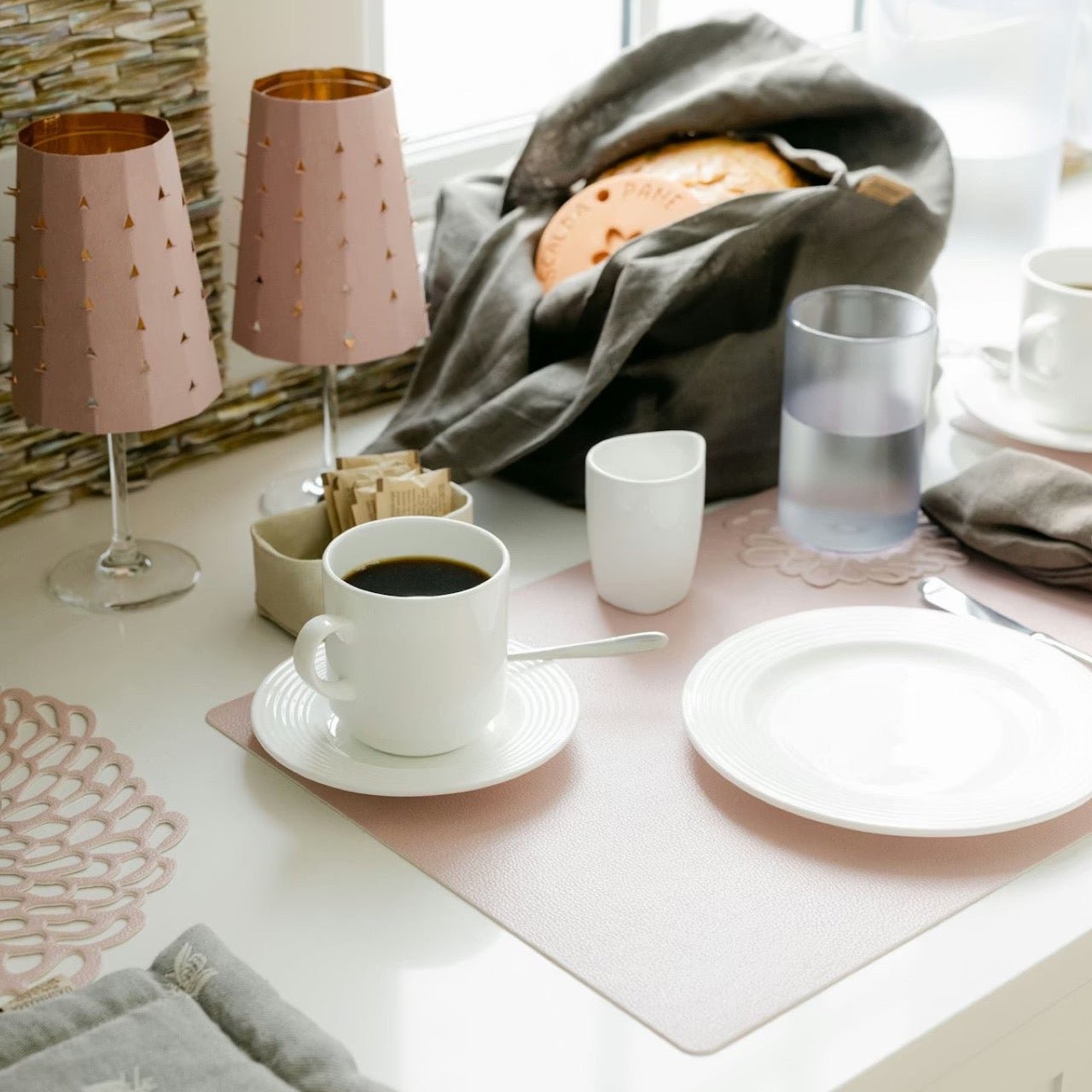Café setting with coffee, plates, and lamps on a table.