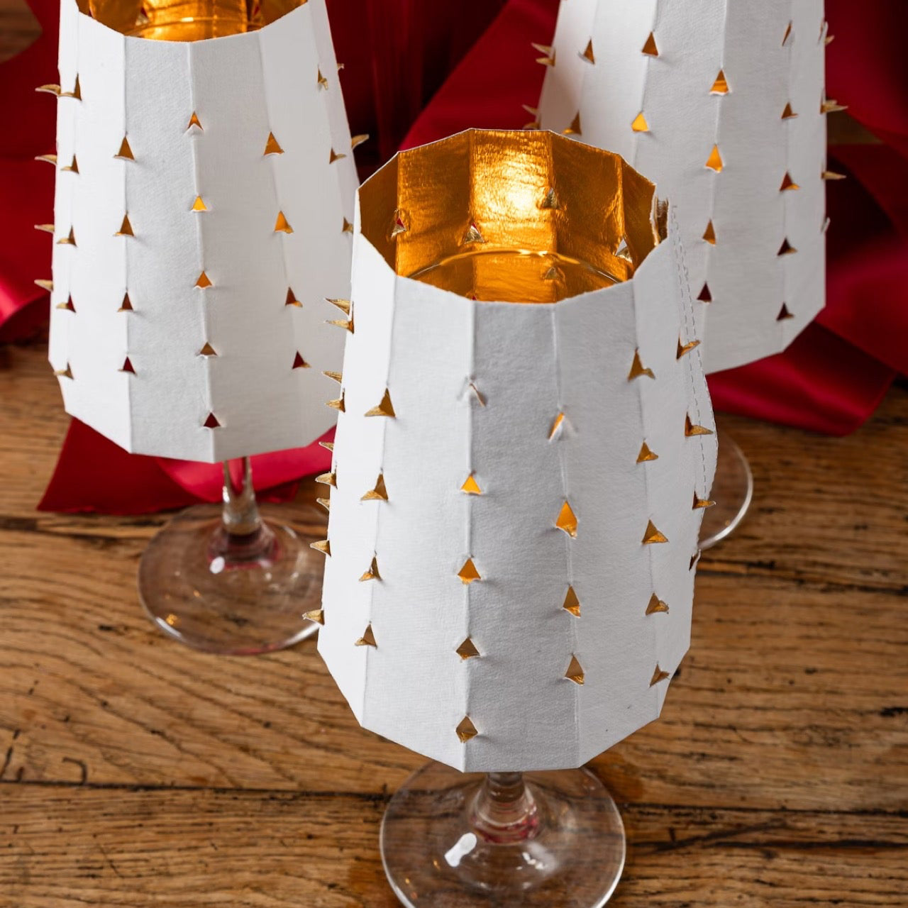 Decorative glass candle holders with gold interior and white geometric pattern on a wooden surface.