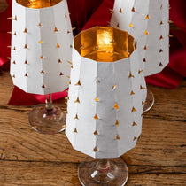 Decorative glass candle holders with gold interior and white geometric pattern on a wooden surface.