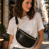 Woman wearing a black woven sling bag on a city street