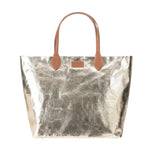 Metallic silver tote bag with brown leather handles on a white background