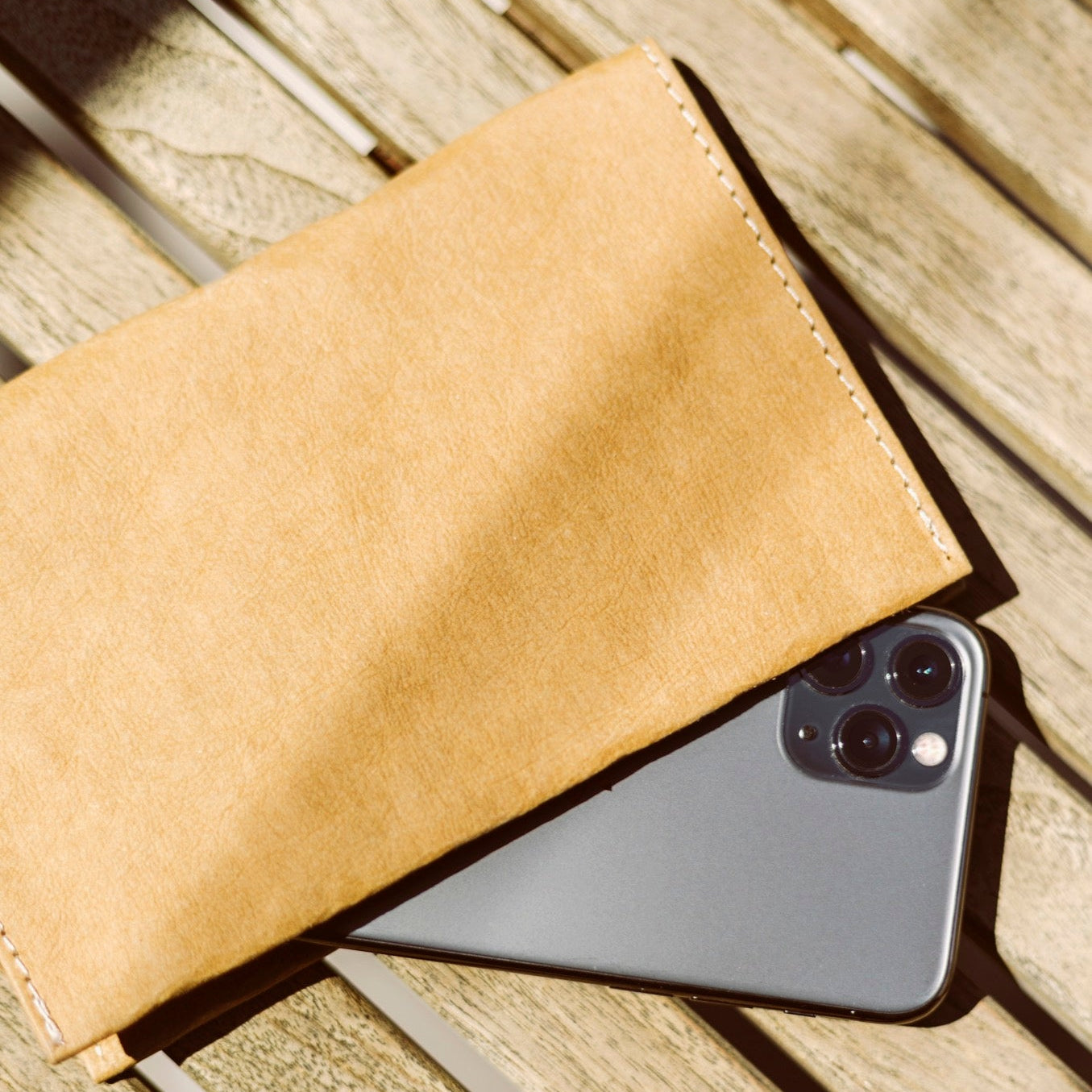 Phone on a wooden surface with a beige wallet
