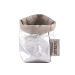 A washable paper bag is shown. The bag is rolled down at the top and features a UASHMAMA logo label on the bottom left corner. The bag pictured is the extra small size in metallic silver.