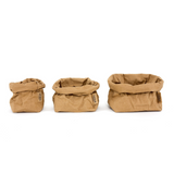 A small, medium and large washable paper bag in a tan colour are lined up from smallest to largest.