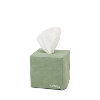 A square tissue box holder made of washable paper is shown, with a white tissue protruding from the top of the box. The UASHMAMA logo is printed in white lettering on the bottom right hand corner of the box. The tissue box cover is sage green.