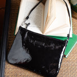 Black clutch bag on a textured surface with an open book underneath