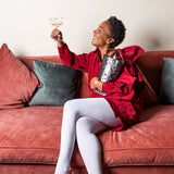 Woman in a red outfit sitting on a couch holding a glass of wine.