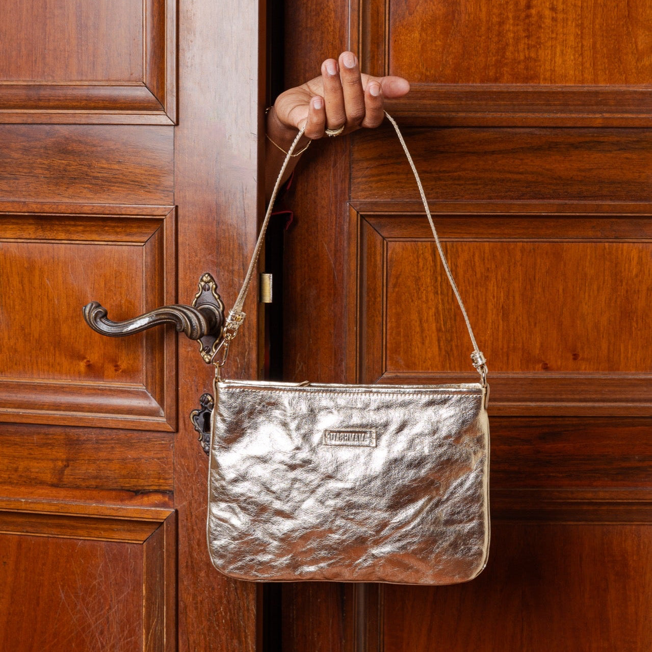 Gold handbag held against a wooden door