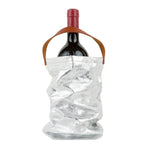 A red wine bottle is shown inside a silver metallic washable paper wine bag. The bag has a small brown leather handle at the top for carrying.