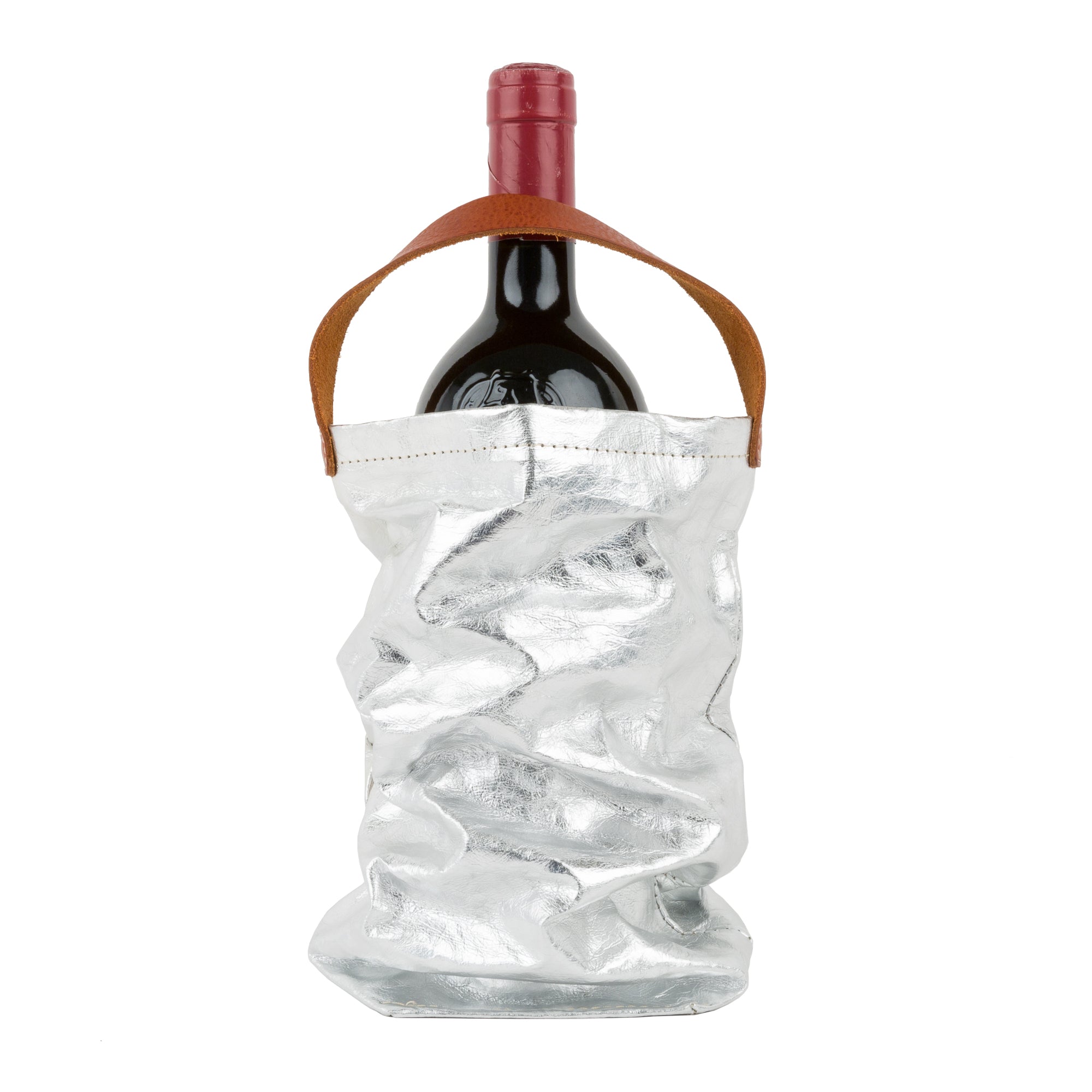 A red wine bottle is shown inside a silver metallic washable paper wine bag. The bag has a small brown leather handle at the top for carrying.