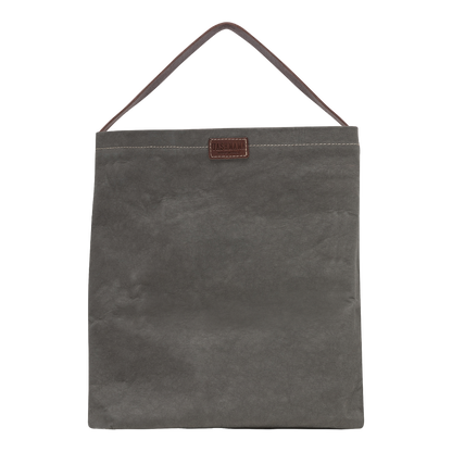 A grey washable paper handbag is shown from the front. It features a singular top handle in chocolate brown, and a brown UASHMAMA logo stamp on the front.