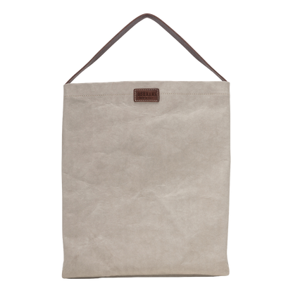 A cream washable paper handbag is shown from the front. It features a singular top handle in chocolate brown, and a brown UASHMAMA logo stamp on the front.