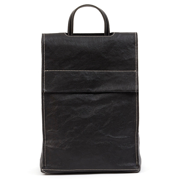 A tall rectangular square-edged washable paper backpack with a front flap and a top handle is shown in black, with white stitching.