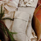 A tan washable paper basket is shown holding two washable paper Christmas stockings, one large and one small. The stockings are pale cream in colour with a platinum metallic cuff, heel and toe.