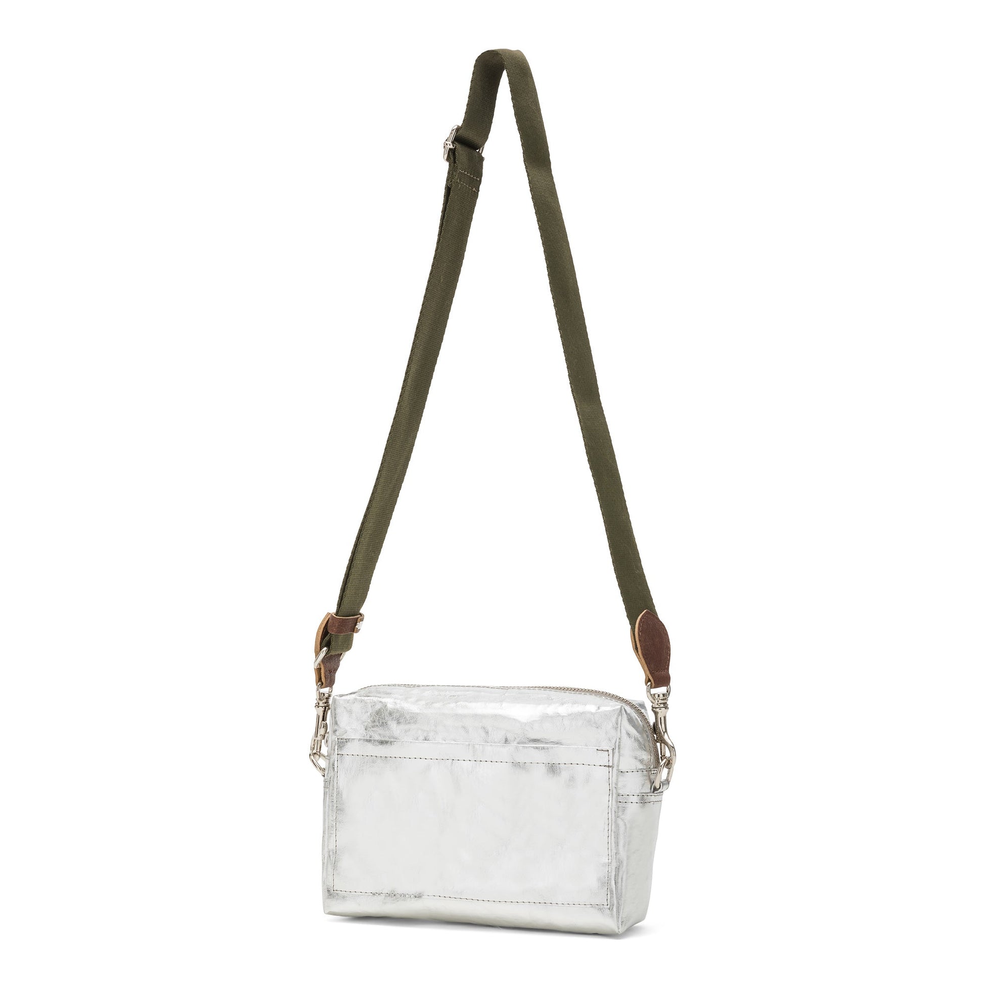 A rectangular washable paper handbag with an external side pocket is shown. The bag has a canvas strap, washable paper details and metal fastening clips to attach the straps to the bag. The bag closes by a zip. The bag shown is metallic silver with an olive strap.