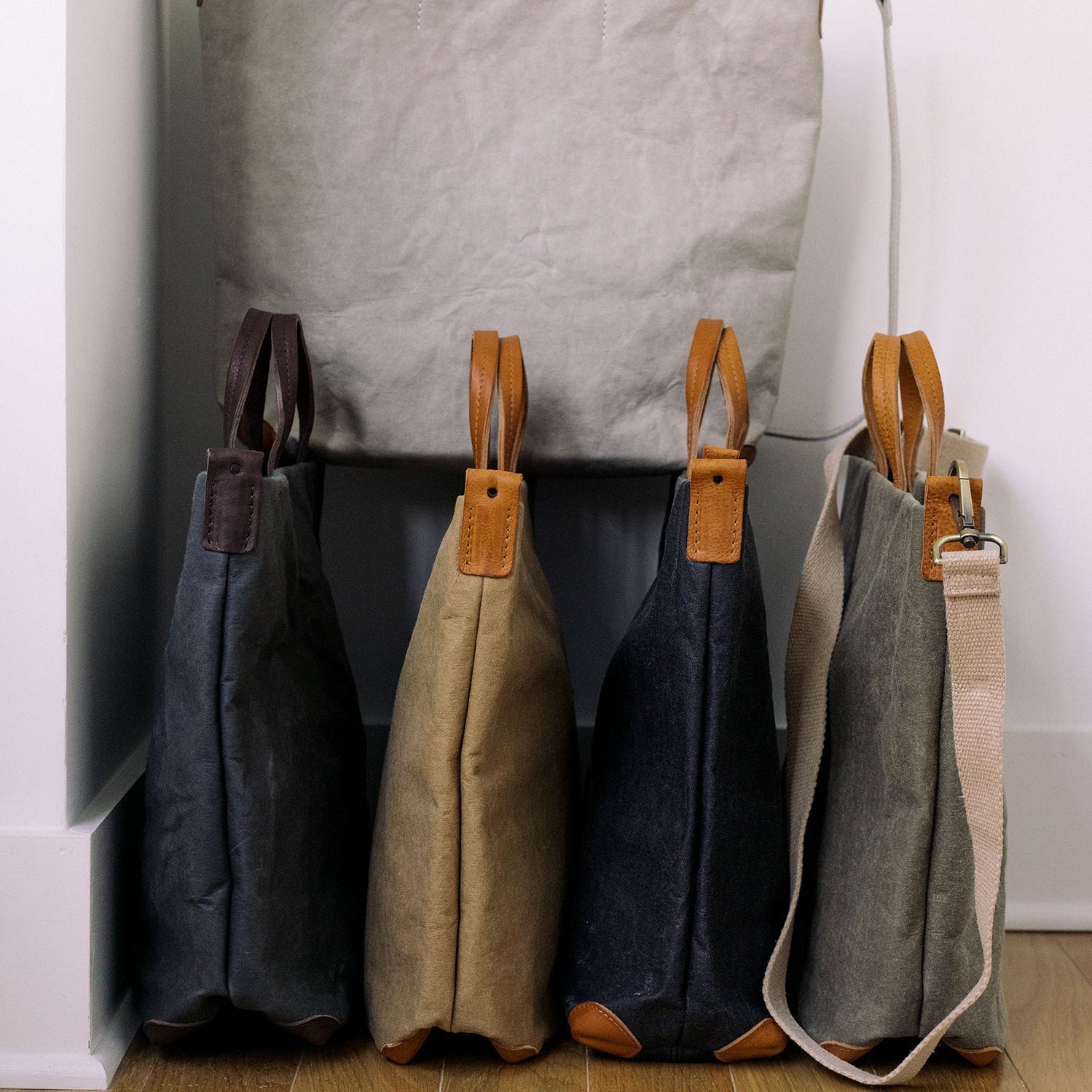 Four washable paper tote bags are shown lined up in a row. The bags are shown from a side angle.