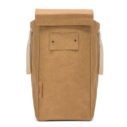 A washable paper recycling bag is shown from the front. The bag has a washable paper  lid which is attached, a washable paper tag attached to the front by two metal studs, and two recycled cotton straps - one on each side. The bag has a UASHMAMA label on the front left side. The bag shown is tan.