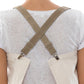 The back of a person is shown. They are wearing a white cotton apron which fastens with olive washable paper braces crossed over the back of the person's shoulders.