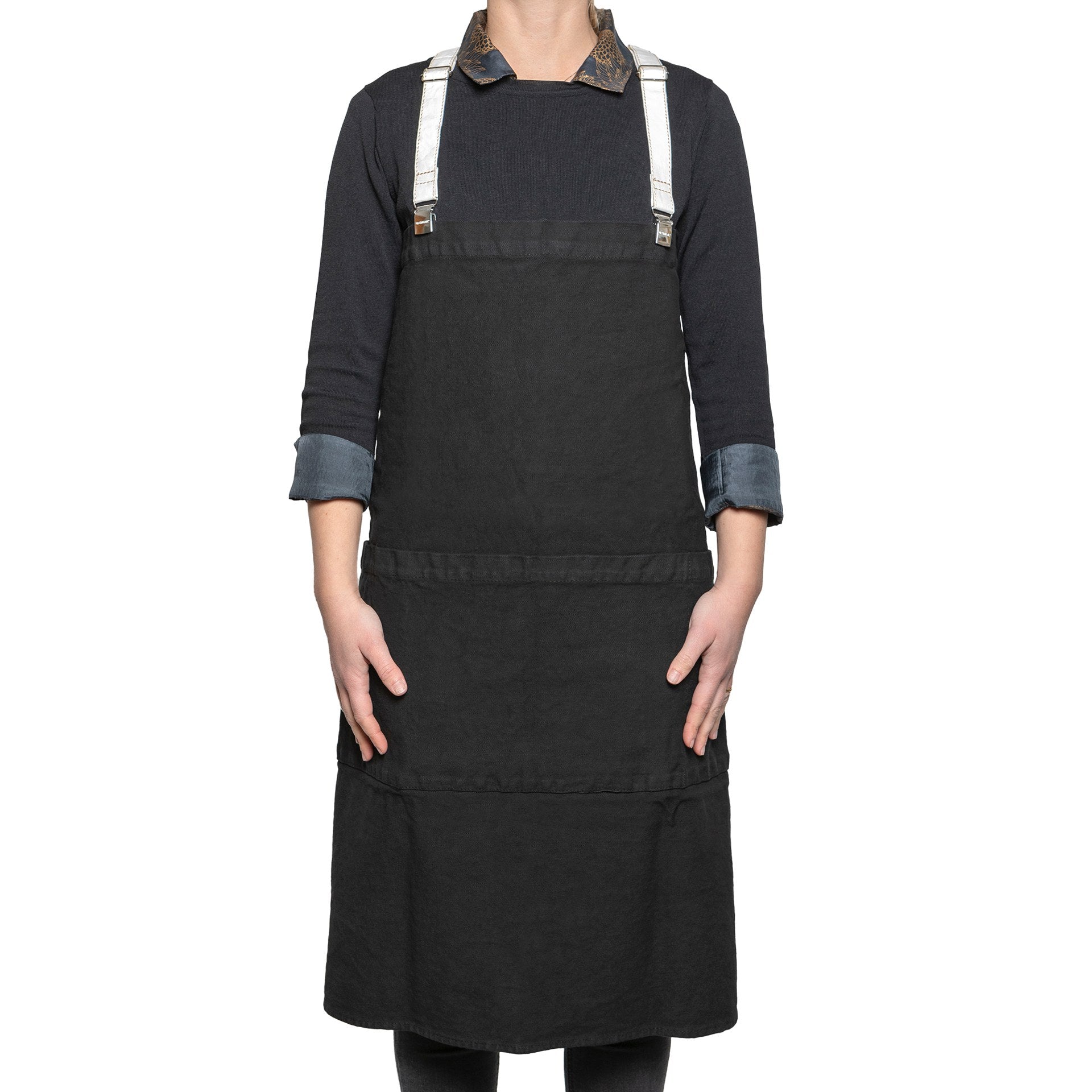 A woman is shown standing in a cotton apron in black. It is fastened with washable paper braces.