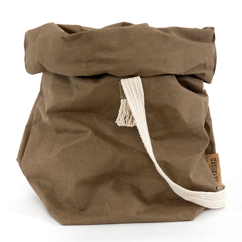 A khaki washable paper bag with a single cotton carry strap in cream. The top is displayed open and rolled down, with a natural toned UASHMAMA logo tab on the right hand side.