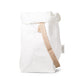 A white washable paper bag with a single cotton carry strap in cream. The top is displayed open and rolled down, with a natural toned UASHMAMA logo tab on the right hand side.