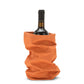A bottle of red wine is shown inside an orange washable paper wine holder.