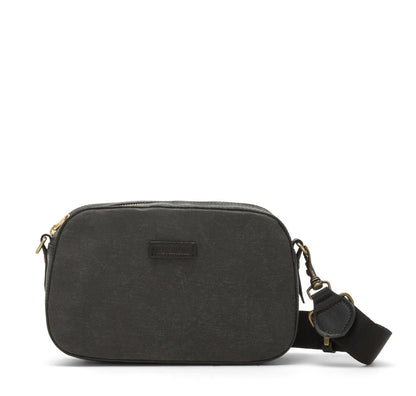 A washable paper cross-body bag is shown with a front tab bearing the UASHMAMA logo in a small font. The bag is shown in dark grey, with a charcoal cotton strap with antique brass hardware.