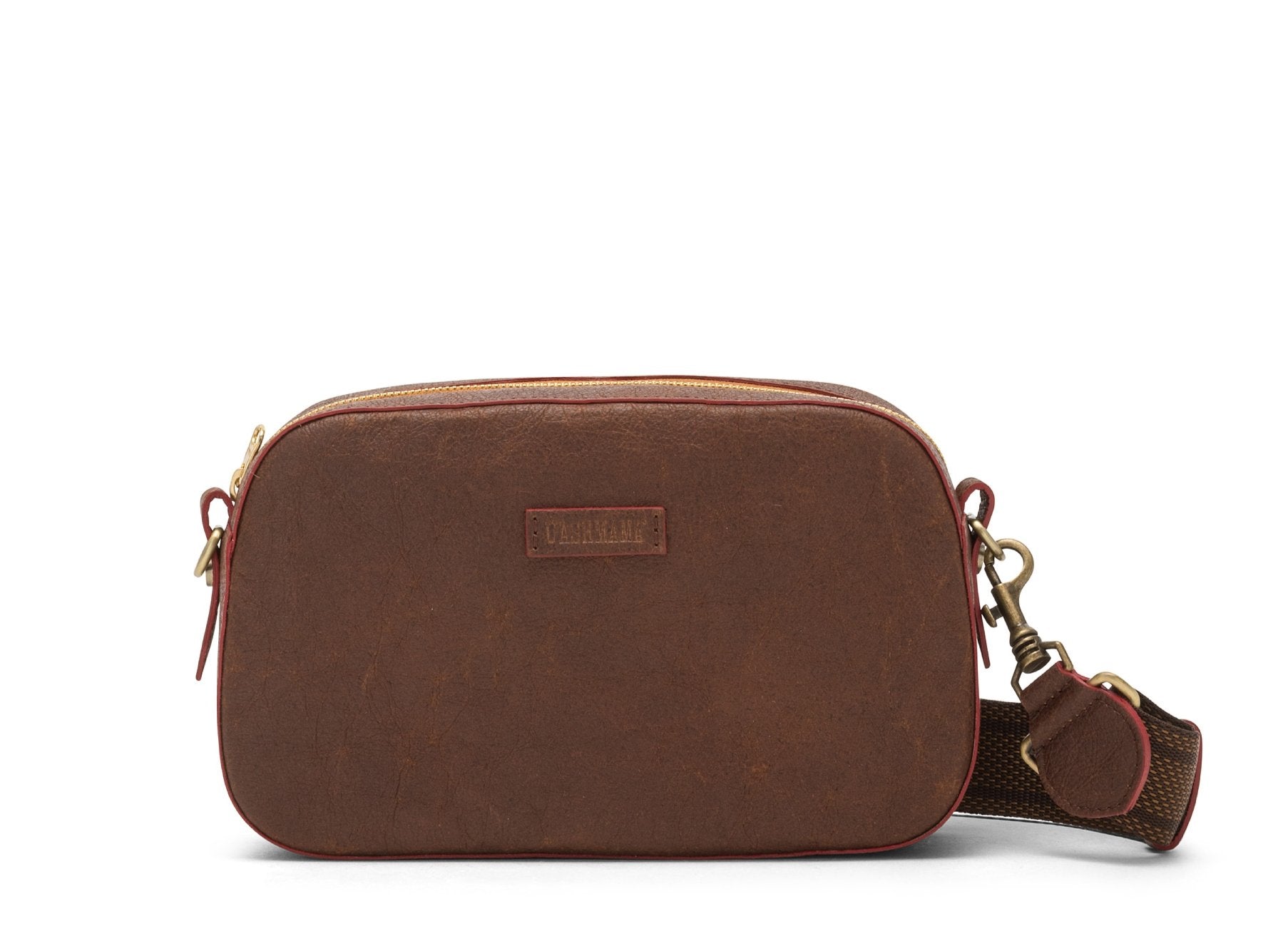 A washable paper cross-body bag is shown with a front tab bearing the UASHMAMA logo in a small font. The bag is shown in brown, with a chocolate toned cotton strap with antique brass hardware.