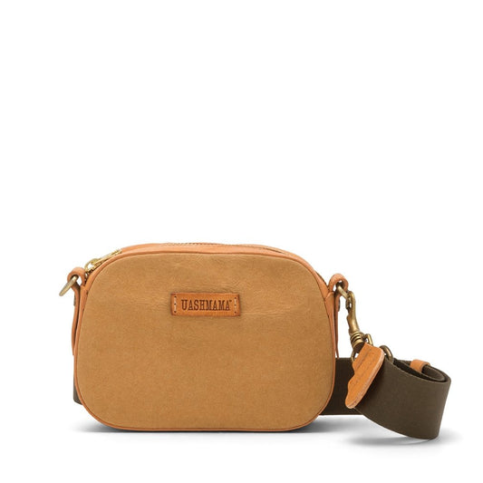 A small washable paper cross-body bag is shown with a front tab bearing the UASHMAMA logo in a small font. The bag is shown in tan, with a khaki cotton strap with antique brass hardware.