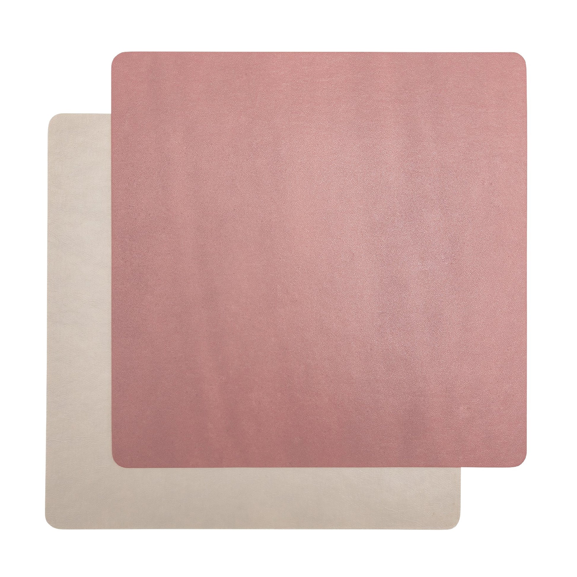 Two square washable paper placemats are shown one on top of the other. The one in the foreground is pink and the one at the rear is beige.