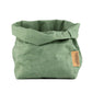 A medium washable paper bag in pale sage green. The top is rolled down. 