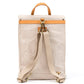 A cream washable paper backpack is shown from the back angle. It features a tan strip across the back, a tan top handle, and cream cotton canvas straps with gold metallic hardware.