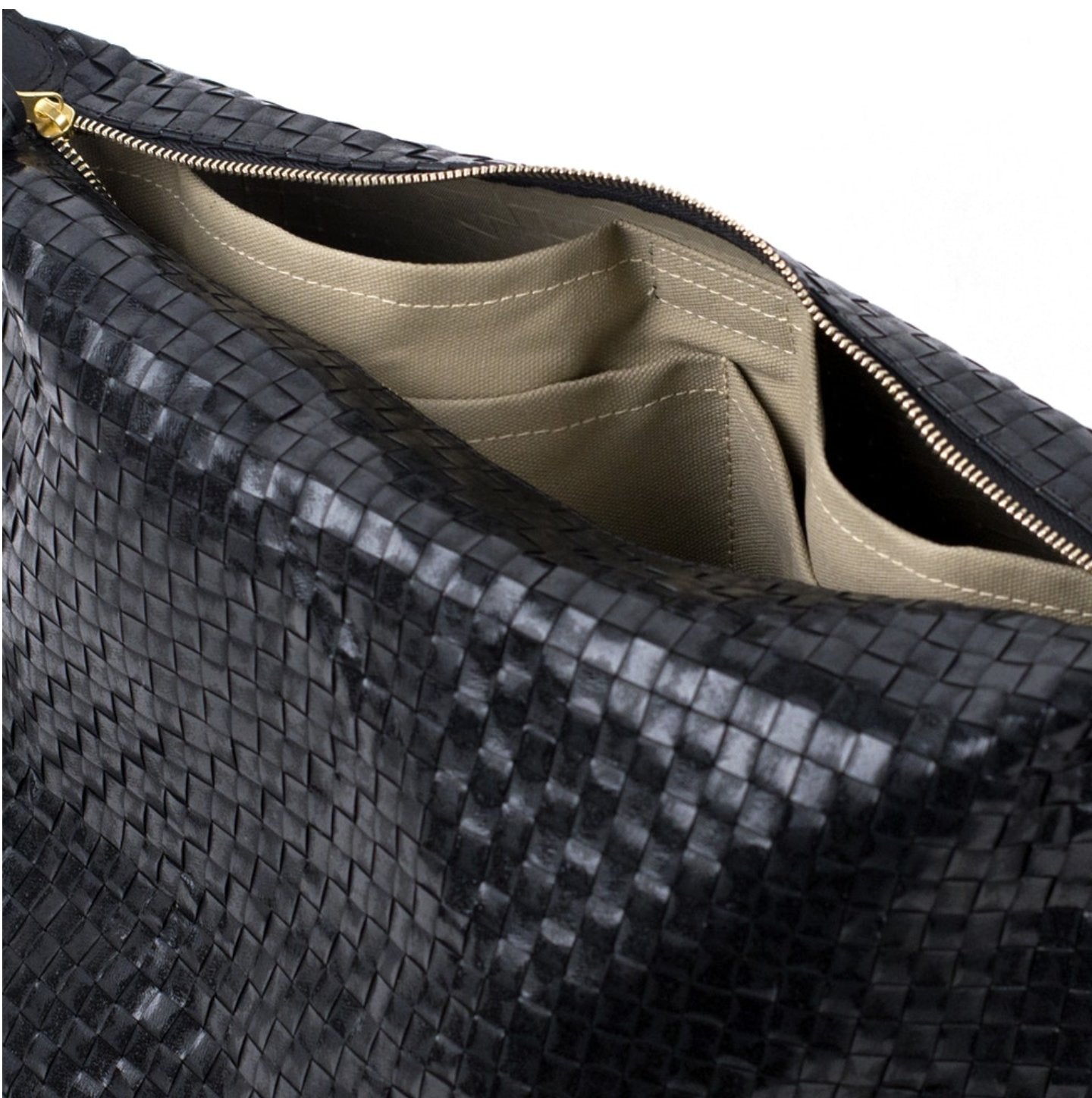 A black woven washable paper tote bag is shown close up from a top angle. It is unzipped to reveal interior pockets in a beige cotton with white stitching.
