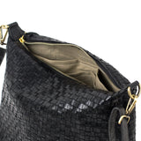 A black woven washable paper handbag is shown unzipped and open to reveal a beige cotton lining with interior pockets.