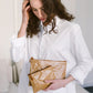 A woman wearing a white shirt is shown holding two washable paper pouches in varying sizes, both tan in colour.
