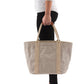 A woman in casual clothing is shown holding a beige washable paper tote bag with two beige cotton canvas top handles.