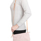 A woman is shown from the side in casual clothing, wearing a small washable paper handbag in dusky pink, with a tan long strap.