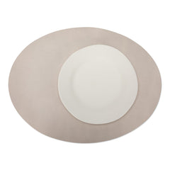 A large oval textured washable paper placemat in beige is shown under a white plate.