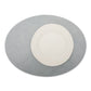 A large oval textured washable paper placemat in grey is shown under a white plate.