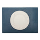 A large rectangular textured washable paper placemat in navy is shown under a white plate.