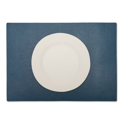 A large rectangular textured washable paper placemat in navy is shown under a white plate.