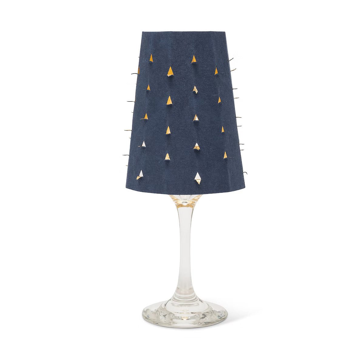 A navy washable paper lampshade with cut out details is shown sitting atop a wine glass.
